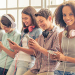 Row of five teenagers listening to their mp3s